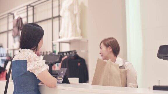 亚洲华人精品店女店主互动与她的客户收银员与信用卡购买结账