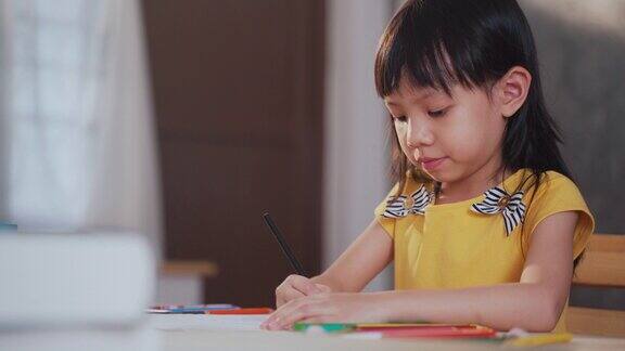 亚洲女孩坐在家里的客厅里学习和画画
