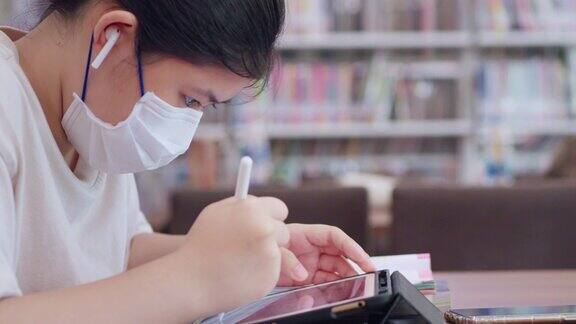 教育年轻的亚洲妇女工作的笔记本电脑在图书馆学习