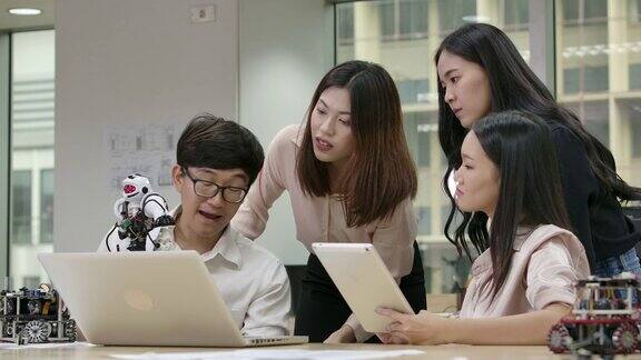 年轻的亚洲创意工程师会议编程协作通用机器人在笔记本电脑车间有技术或创新观念的人