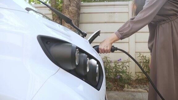 慢镜头拍摄一名面目全非的亚洲女子在给电动汽车充电