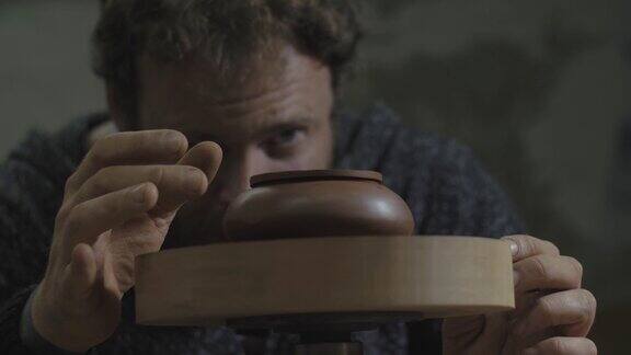 一名工匠将宜兴陶土茶壶放在木轴上旋转宜兴茶道手工陶壶褐色陶器茶壶4k的视频59.94帧秒