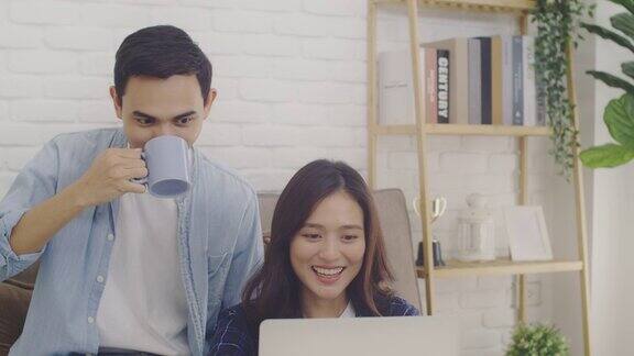 年轻的亚洲情侣情侣对着笔记本电脑上的摄像头一起视频通话在一个房间在家里的背景4k慢动作