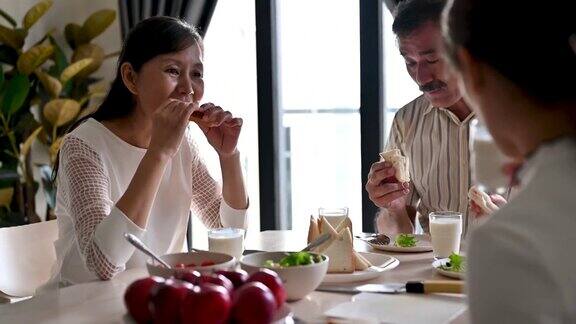 快乐的亚洲家庭享受在厨房的健康早餐时间
