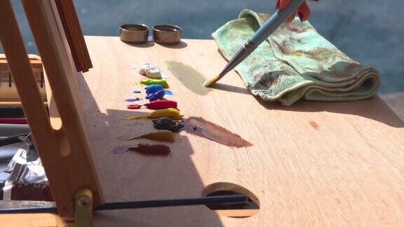 一位艺术家在海边的空气中画画在画架前用画笔混合油画颜料的颜色