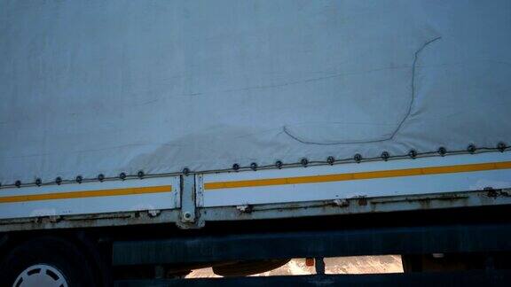 带货运拖车的卡车在高速公路上行驶并运输货物的侧视图穿过乡村公路开往目的地的卡车卡车拖车的特写货物运输慢动作