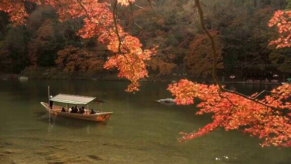 在岚山秋叶林中的桂河上的一艘当地船只