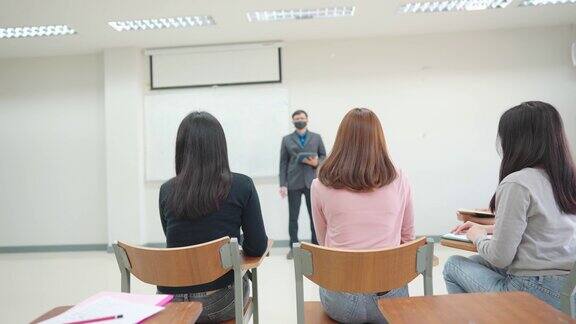 在大学的教室里老师站在教室的前面教学生学生戴口罩预防病毒感染