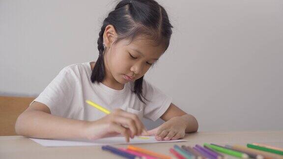 可爱的亚洲女孩在纸上画画在家里享受色彩孩子在家上学