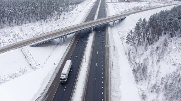 在积雪覆盖的树木中桥下的道路上卡车在运输货物