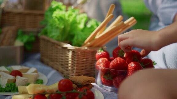 美味的夏日野餐午餐特写认不出来的手拿着草莓