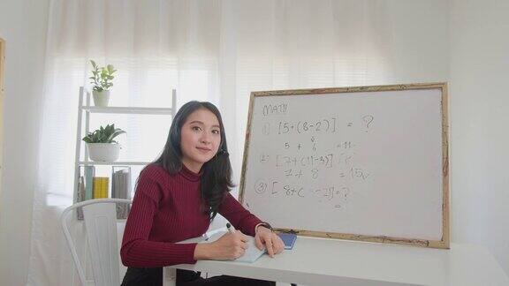 肖像美丽的亚洲女人微笑和看相机微笑的亚洲女性教师数学课在线家庭教育