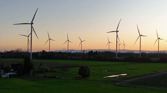 夕阳下的风力涡轮机农场鸟瞰图可再生能源生产无人机视频