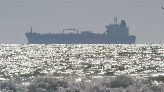 海浪和海鸥的慢动作拍摄附近的亨廷顿海滩在南加州与石油(石油)油轮在地平线上在远处