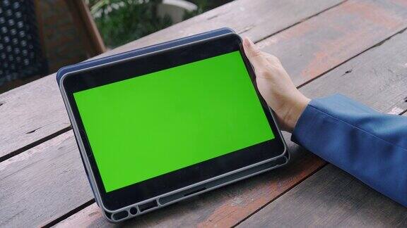 一个女人手里拿着一个有绿色屏幕的平板电脑的特写