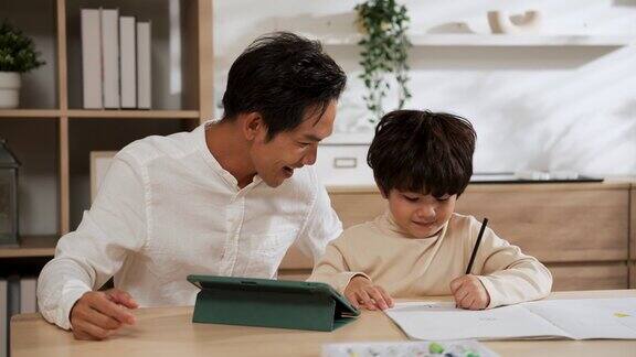 亚洲父亲看着儿子在纸上画画