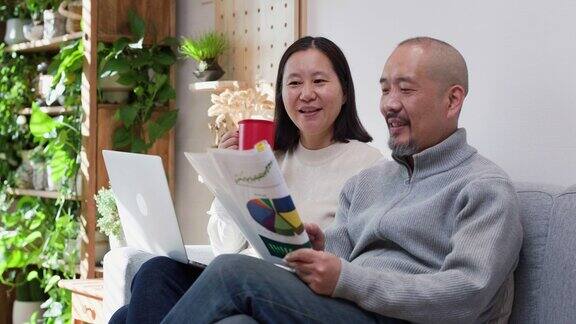 亚洲幸福的夫妇在家里用笔记本电脑管理他们的财务
