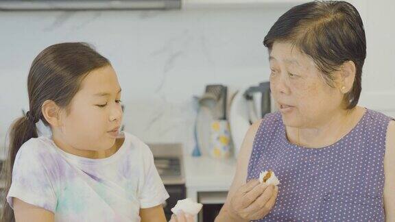 亚洲的祖母和孙女在蒸包子后吃包子多代家庭一起在家做饭