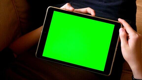 躺在沙发上用绿色屏幕为色度键的数字平板电脑的人