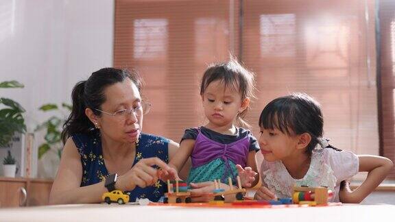 亚洲母亲在周末活动中与她的两个女儿玩玩具家人一起在公寓的客厅里度过时光