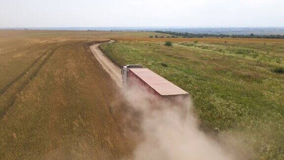 卡车货运卡车在农业麦田之间的土路上行驶的鸟瞰图收获季节联合收割机收获后的谷物运输