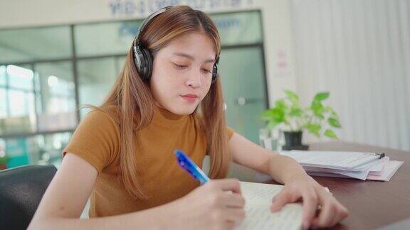 一名年轻的亚洲大学生戴着耳机在家在线学习在病毒爆发期间没有上大学