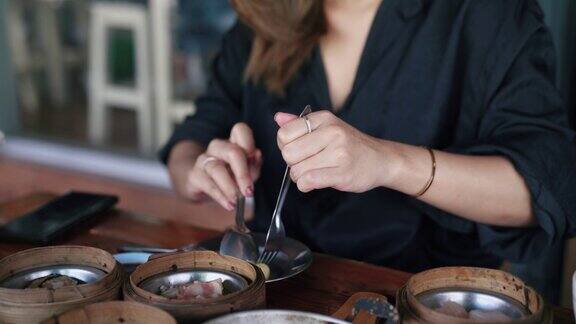 亚洲妇女把虾饺进入她的盘子前调味酱