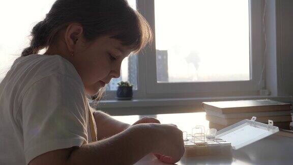 有创造力的孩子在餐桌上制作珠子手镯