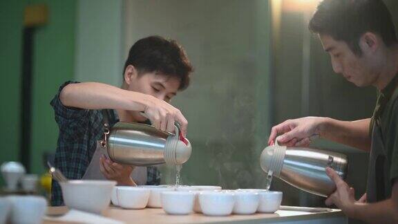 2.专业亚洲华人咖啡师将热水倒入陶瓷咖啡杯中为咖啡的拔火罐准备咖啡品质测试