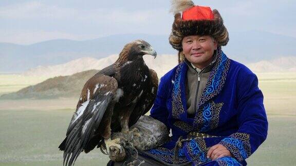 在西蒙古的巴扬-奥尔吉伊附近身穿传统服装的哈萨克猎鹰者手臂上抱着一只金鹰