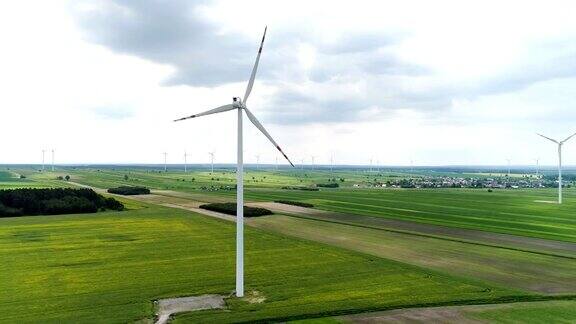 风力涡轮机矗立在油菜和小麦盛开的田野上