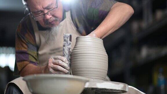 亚洲华人高级泥塑艺术家在他的工作室与纺织陶轮工作