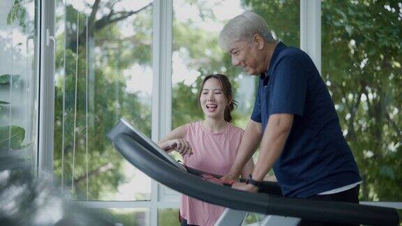 老人在健身俱乐部和教练一起制定健身计划在跑步机上锻炼的老人在健身房康复期间与他的教练交谈