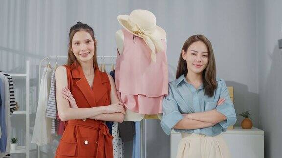 两名亚洲美女的肖像后自信地站在镜头前卖衣服年轻有魅力的商务人士通过虚拟在线直播工作看着镜头