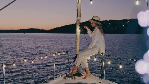 时尚的女子在帆船甲板上享受着被细绳灯照亮的景色