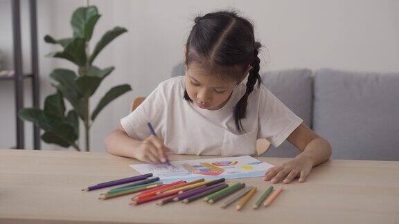 亚洲孩子在家里用彩色铅笔学习绘画和上色