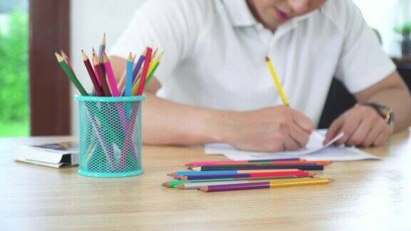 亚洲帅哥的手用彩笔在成人涂色书的一页纸上作画创造艺术家的技巧和想象力青少年周末与休闲活动