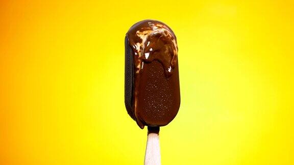 慢镜头:在黄色背景上融化的巧克力冰淇淋