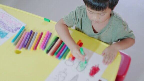 快乐的小男孩在家里用马克笔在画纸上画画