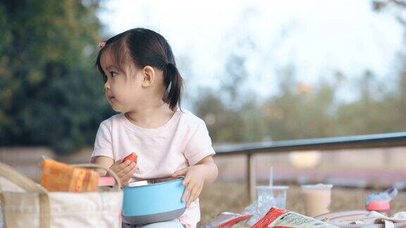 亚洲小女孩在公园野餐吃草莓
