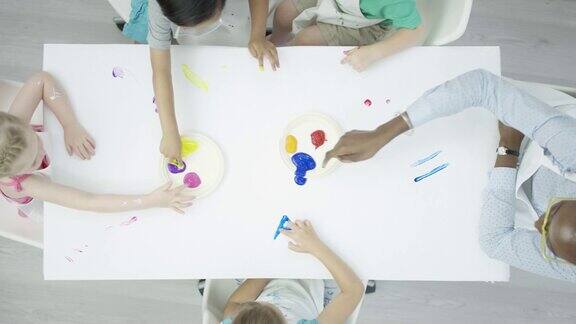 一群孩子在干净的白色桌子上画手指画