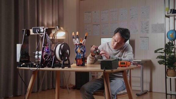 亚洲男性用3D打印握着和固定电路板同时在家里修复半机械人的手