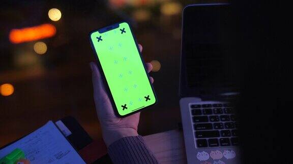 手持智能手机使用和显示绿色屏幕在夜间