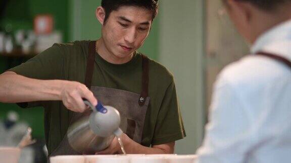 专业的亚洲华人咖啡师品酒师将热水倒入陶瓷咖啡杯中准备拔杯咖啡品质测试