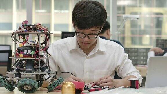 年轻的亚洲电子开发工程师与机器人一起工作在车间测量机器人原型电路中的信号有技术或创新观念的人