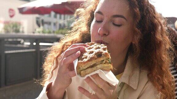 年轻女子吃快餐三明治女人在咖啡馆吃午饭