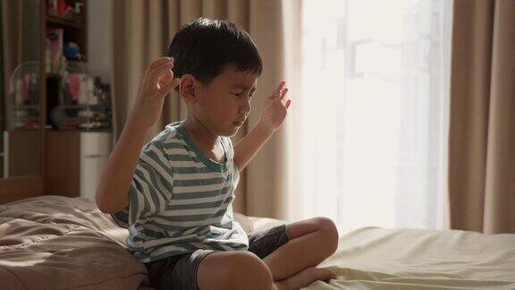 亚洲男孩在家里的卧室里练习冥想的特写