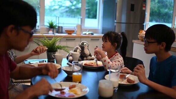 亚洲华人年轻家庭和两个孩子一起吃早餐周末早上一起在厨房