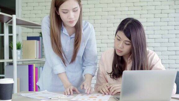 迷人、聪明、有创意的亚洲商务女性穿着时尚休闲装坐在办公桌上用笔记本电脑工作女性在办公室工作