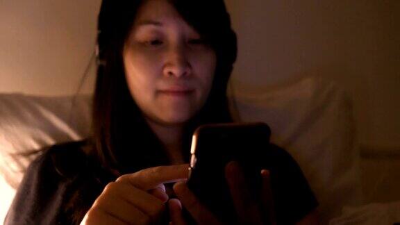 一名泰国女子在睡觉前一边听音乐一边用智能手机和朋友聊天